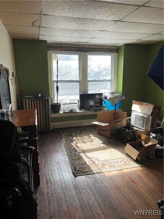 interior space featuring a drop ceiling, radiator, and hardwood / wood-style flooring