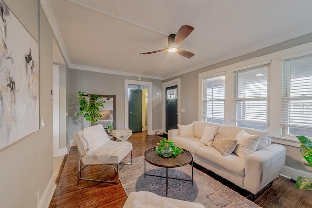 living room featuring a healthy amount of sunlight, crown molding, baseboards, and wood finished floors