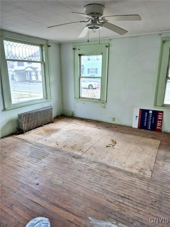 unfurnished room featuring radiator, ceiling fan, and hardwood / wood-style flooring