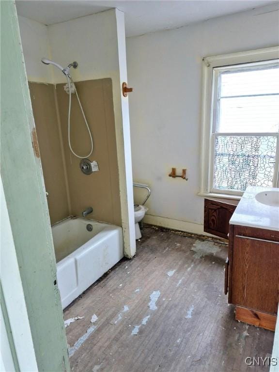 bathroom with baseboards, toilet, vanity, wood finished floors, and washtub / shower combination