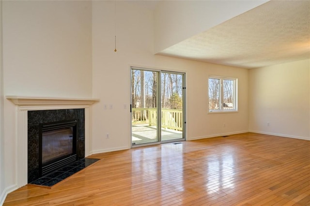 unfurnished living room featuring a fireplace, baseboards, and wood-type flooring