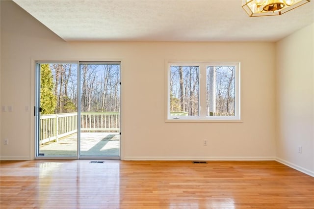 empty room featuring visible vents, a healthy amount of sunlight, and light wood-type flooring