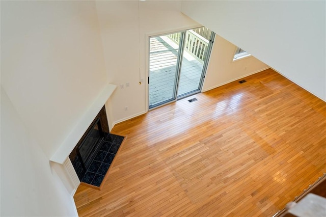 unfurnished living room with visible vents, wood-type flooring, and baseboards