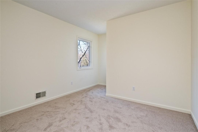 carpeted spare room featuring visible vents and baseboards