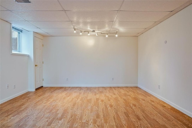 spare room with light wood-type flooring, a drop ceiling, baseboards, and track lighting