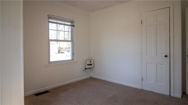 carpeted spare room featuring visible vents and baseboards