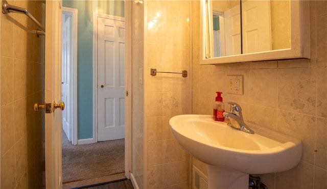 bathroom featuring tile walls and a sink