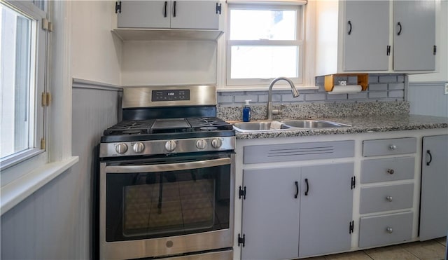 kitchen featuring a sink, under cabinet range hood, and stainless steel range with gas stovetop