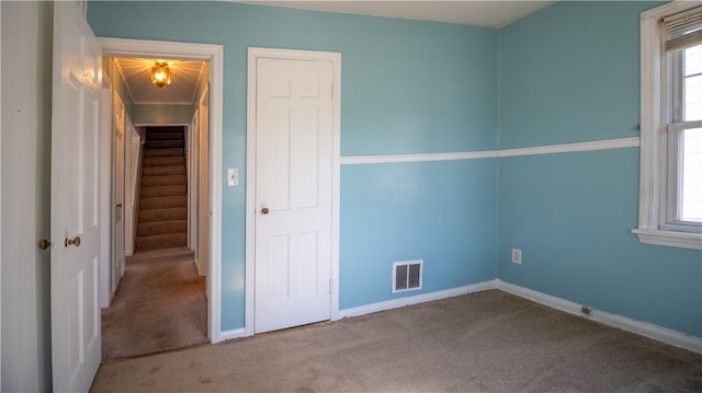 unfurnished bedroom with visible vents, multiple windows, and carpet