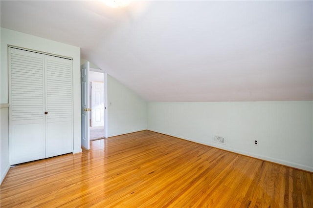 additional living space with visible vents, light wood-style flooring, and vaulted ceiling