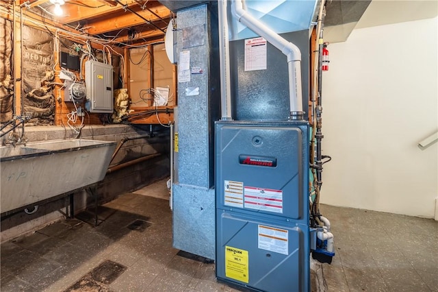 utility room with electric panel, heating unit, and a sink