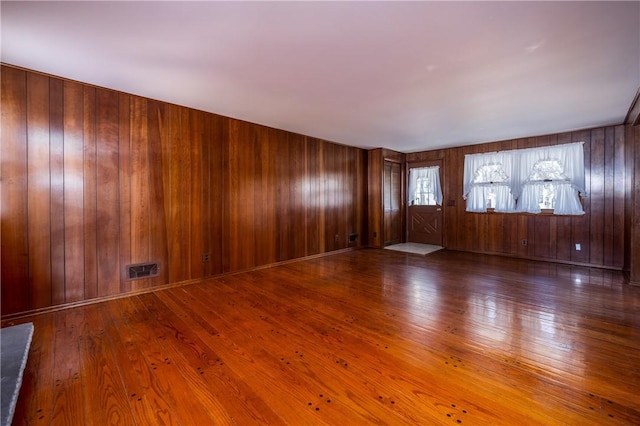 interior space featuring visible vents, baseboards, wooden walls, and hardwood / wood-style flooring