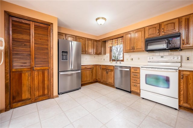 kitchen featuring light countertops, brown cabinetry, backsplash, and stainless steel appliances