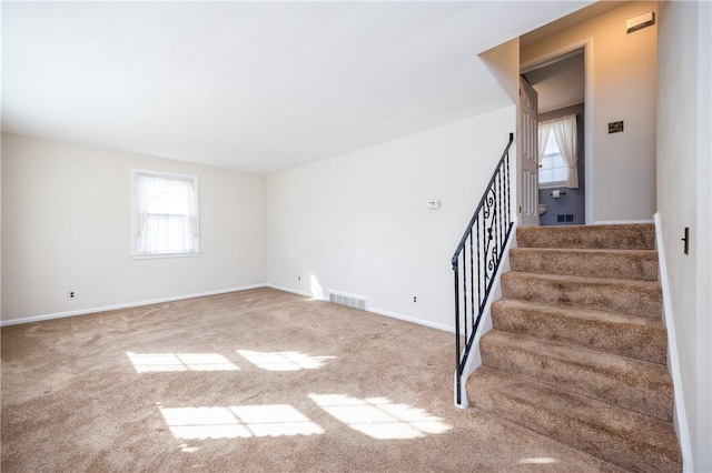 stairway with baseboards, visible vents, and carpet floors