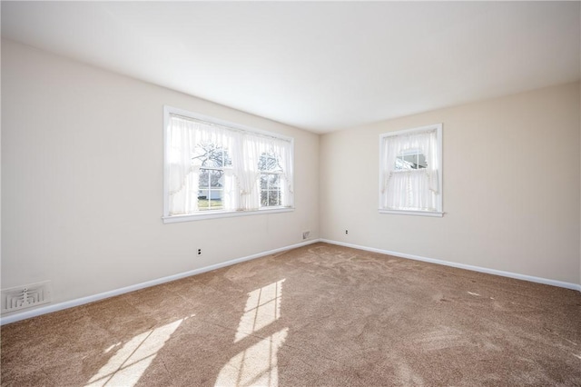 carpeted spare room with visible vents and baseboards