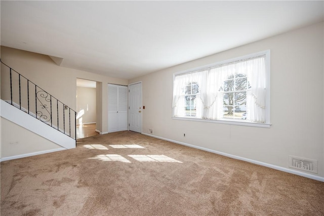 unfurnished living room featuring visible vents, stairs, baseboards, and carpet floors