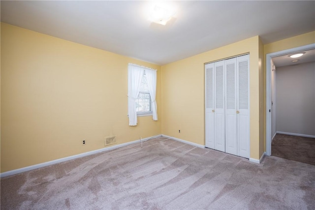 unfurnished bedroom featuring visible vents, baseboards, a closet, and carpet flooring