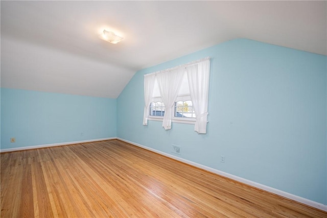 additional living space with vaulted ceiling, baseboards, and wood finished floors