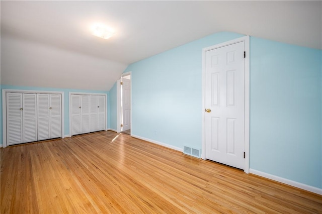 bonus room with vaulted ceiling, light wood-style floors, visible vents, and baseboards