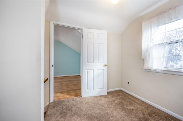 unfurnished bedroom featuring baseboards, carpet flooring, and vaulted ceiling