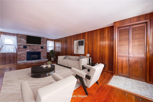 living room featuring wooden walls, a fireplace, and wood-type flooring