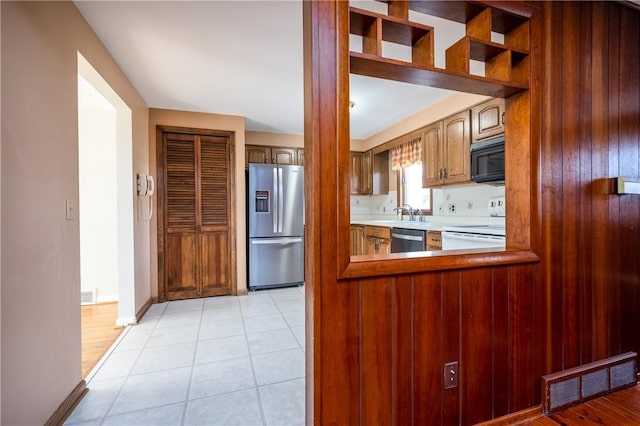 kitchen featuring light tile patterned floors, baseboards, visible vents, appliances with stainless steel finishes, and brown cabinets