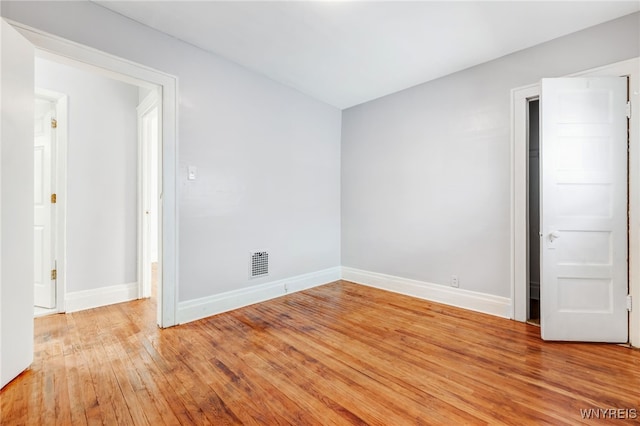 spare room featuring baseboards, visible vents, and light wood finished floors