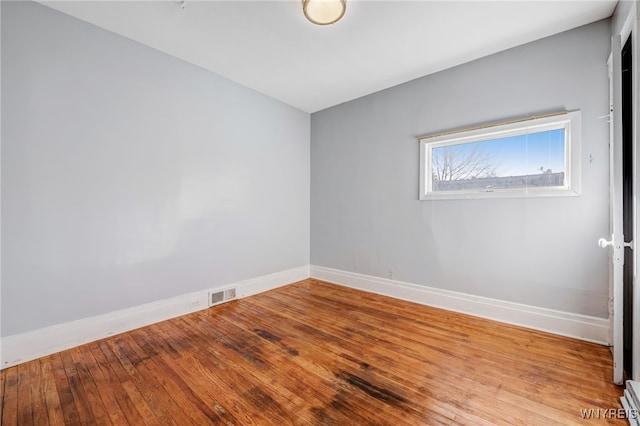 spare room with visible vents, baseboards, and hardwood / wood-style flooring