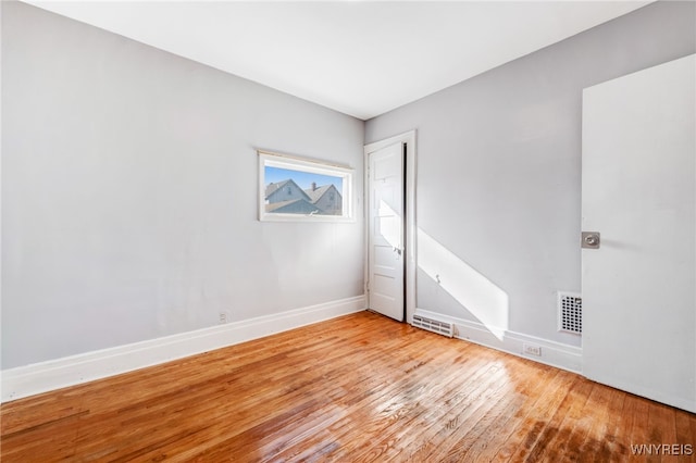 empty room with visible vents, baseboards, and wood-type flooring