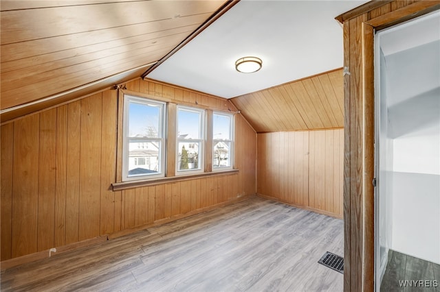 additional living space with visible vents, wood walls, wood ceiling, lofted ceiling, and wood finished floors