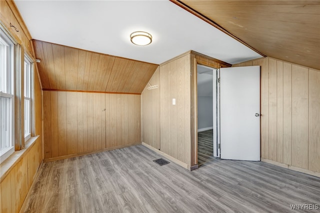 bonus room featuring lofted ceiling, wood finished floors, visible vents, and wood walls