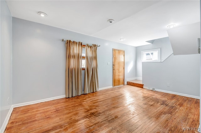 unfurnished room featuring hardwood / wood-style flooring, baseboards, and visible vents