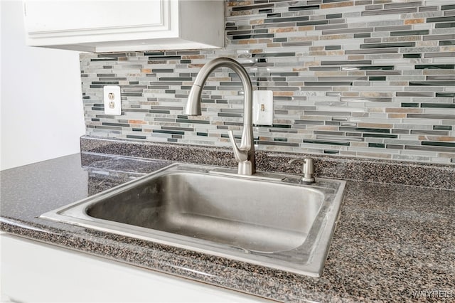 interior details with tasteful backsplash, dark countertops, and a sink