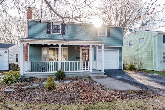 traditional-style home with aphalt driveway, covered porch, a chimney, and a garage