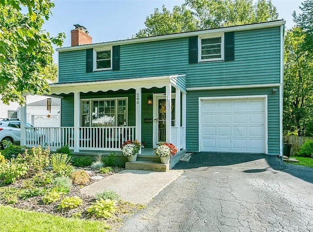 view of front facade with a porch, an attached garage, driveway, and a chimney