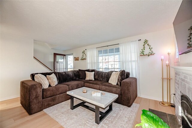 living area with a fireplace, light wood-style floors, and a textured ceiling