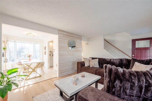 living area with light wood-style floors, a textured ceiling, and stairs