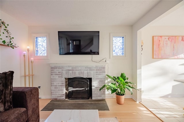 living room with wood finished floors, a fireplace, baseboards, and a textured ceiling