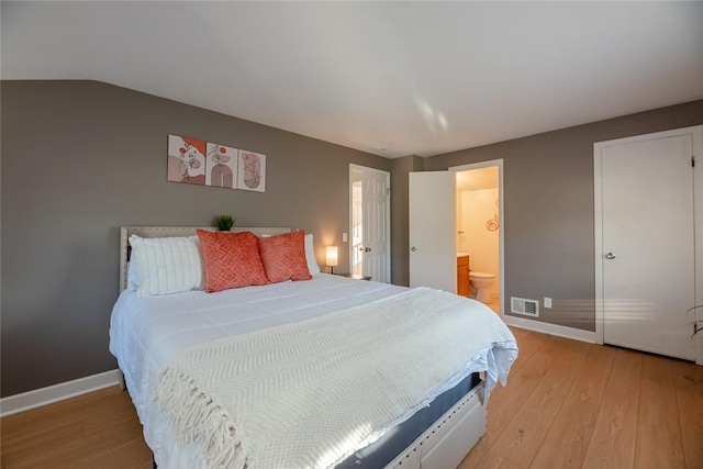 bedroom with visible vents, connected bathroom, baseboards, lofted ceiling, and light wood-style flooring