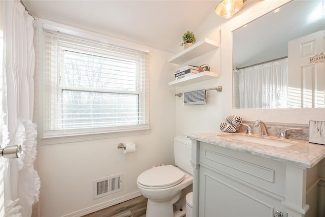 bathroom with visible vents, baseboards, toilet, wood finished floors, and vanity