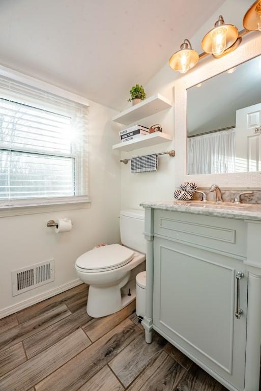 full bath with visible vents, toilet, wood finished floors, and vanity