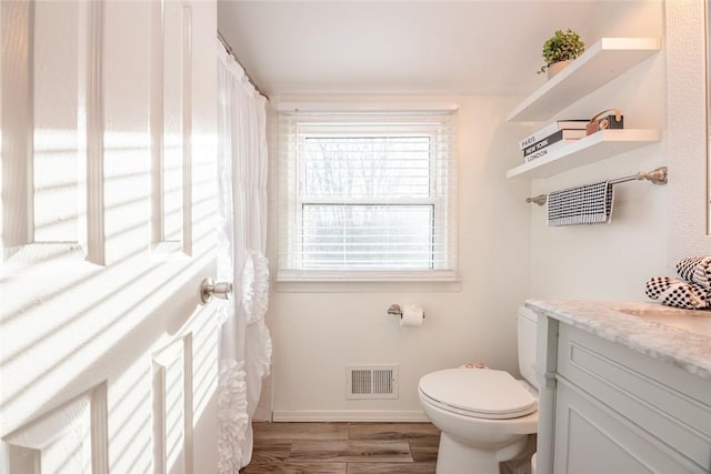 bathroom with visible vents, toilet, wood finished floors, baseboards, and vanity