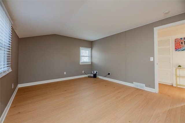 unfurnished room with lofted ceiling, light wood-style flooring, baseboards, and visible vents