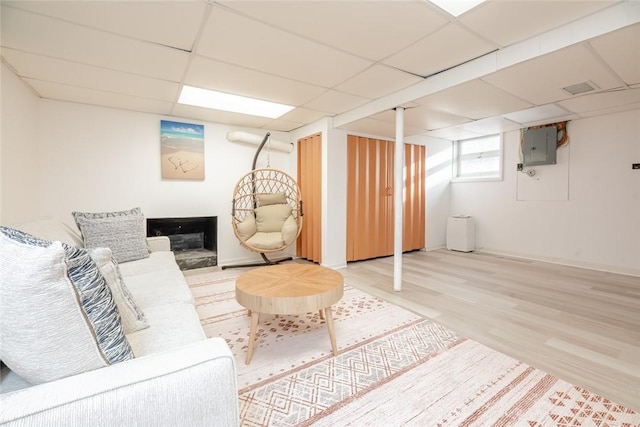 living room featuring electric panel, wood finished floors, and a paneled ceiling