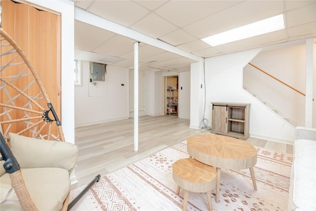 living room with light wood finished floors, stairway, electric panel, and a drop ceiling