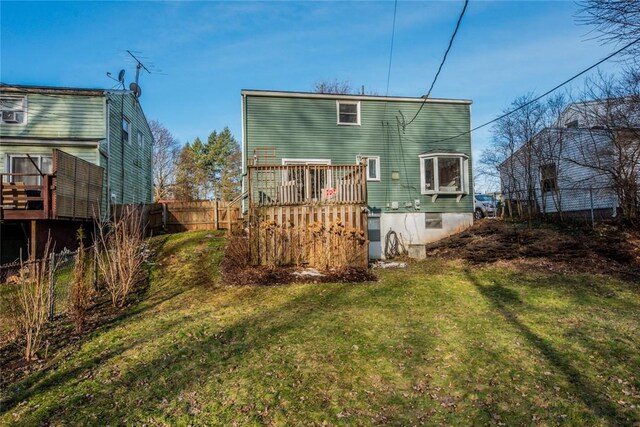 back of property featuring a yard, a deck, and fence