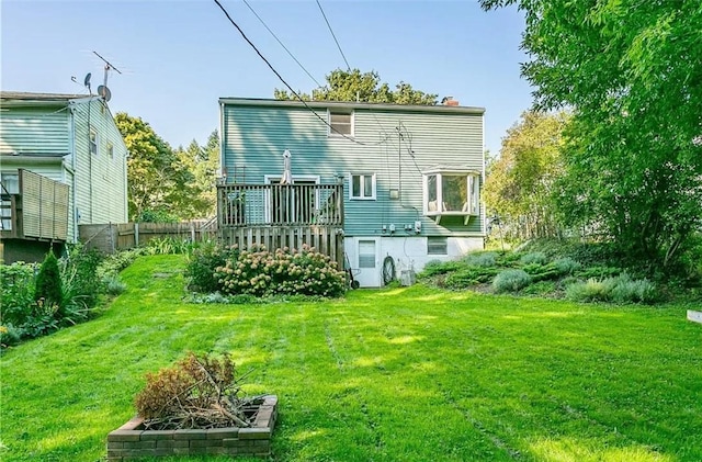 back of house with a yard, a wooden deck, a chimney, and fence