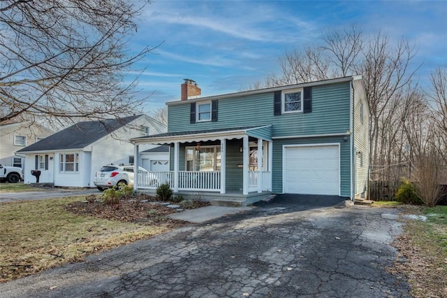 view of front of property featuring aphalt driveway, a porch, a chimney, and an attached garage