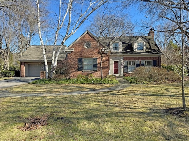 new england style home with brick siding, a front lawn, concrete driveway, a chimney, and a garage