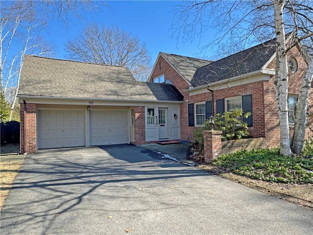 view of front of property with an attached garage, brick siding, driveway, and a shingled roof